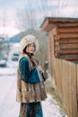 Young woman walks on snowbound street along wooden fence