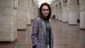 A young woman walks in the subway. A girl in a coat and glasses Royalty Free Stock Photo