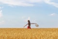 Young woman walks through wheat field with hat in hands and enjoying Sunny day. Freedom and rest Royalty Free Stock Photo