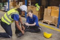young woman warehouse worker accident leg injury slip and fall ankle sprain friend help support Royalty Free Stock Photo