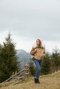 Young woman in warm clothes near conifer forest.