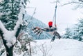 A happy young woman in warm clothes and Red Cap swinging on a forest tree swing with picturesque snowy mountain view. Wintertime Royalty Free Stock Photo