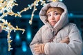 Woman in a warm down jacket and thermal underwear is frozen and shivering during a severe frost while walking around the New Royalty Free Stock Photo