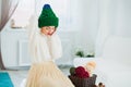 Young woman in warm hand knitted hat at home. Pretty lady in big green cap, smiling happily. Beautiful girl knitting in cozy flat