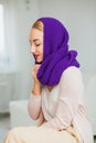 Young woman in warm purple hand knitted hat at home. Royalty Free Stock Photo