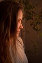 Young woman looking at camera in warm rays of sunset. Warm calm portrait of girl indoor. light and shadow on the face