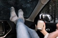 Young woman in warm socks with coffee resting inside car Royalty Free Stock Photo