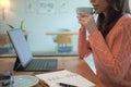 Young woman in warm sweater drinking hot coffee and using computer tablet at home. Royalty Free Stock Photo