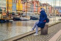 Woman in warm winter clothes sits and looks at the Nyhavn embankment. Copenhagen, Denmark Royalty Free Stock Photo