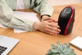 Young woman warming hands near compact electric heater at wooden table, closeup Royalty Free Stock Photo