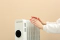 Young woman warming hands near modern electric heater on beige background, closeup. Space for text Royalty Free Stock Photo