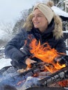 Young woman warming up by the fire pit during cold winter day Royalty Free Stock Photo