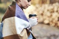 Woman warmly dressed holding coffee cup in the forest autumn