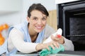 Young woman washes microwave oven