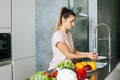 Young woman washes vegetables