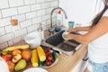 Young woman washing dishes manually in kitchen. Royalty Free Stock Photo