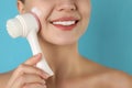 Young woman washing face with brush and foam on light blue background, closeup. Cosmetic products Royalty Free Stock Photo