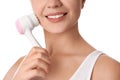 Young woman washing face with cleansing brush on background, closeup. Cosmetic product