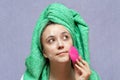 Young woman washing face with silicone pink brush and cleansing foam. Cosmetic products