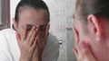 Young woman is washing her face in front of the mirror in bathroom.