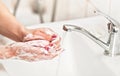 Young woman washing her hands under water tap faucet with pink soap bar. Detail on suds covered skin. Personal hygiene concept - Royalty Free Stock Photo