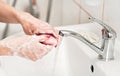 Young woman washing her hands under water tap faucet with pink soap bar. Detail on suds covered skin. Personal hygiene concept - Royalty Free Stock Photo