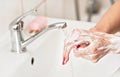 Young woman washing her hands under water tap faucet with soap. Detail on suds covered skin. Personal hygiene concept - Royalty Free Stock Photo