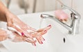 Young woman washing her hands under water tap faucet with soap. Detail on suds covered skin. Personal hygiene concept - Royalty Free Stock Photo