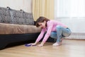 Young woman washing wooden floor with blue floorcloth