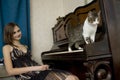 The young woman is watching cat walking on piano