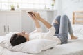 Young woman watching the  mobile phone and lying on the bed at home Royalty Free Stock Photo