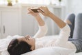 Young woman watching the  mobile phone and lying on the bed at home Royalty Free Stock Photo