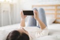 Young woman watching the  mobile phone screen and lying on the bed at home Royalty Free Stock Photo