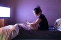 Young woman watching movie on television in bed at night. Teenage girl at home in her modern bedroom with headphones and digital t Royalty Free Stock Photo