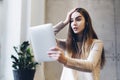 Young woman watching shocking content online on Internet. Emotional girl looking at tablet screen in surprise. Girl watching video