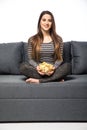 Young woman watching TV and eating chips sitting on sofa Royalty Free Stock Photo