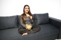 Young woman watching TV and eating chips sitting on sofa Royalty Free Stock Photo