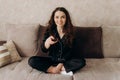 Young woman watching TV in the room while sitting on sofa. View channels.