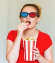 Young woman watching tv while sitting on a sofa with 3d glasses and popcorn with pleasure Royalty Free Stock Photo