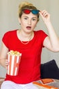 Young woman watching tv while sitting on a sofa with 3d glasses and popcorn with pleasure Royalty Free Stock Photo