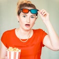 Young woman watching tv while sitting on a sofa with 3d glasses and popcorn with pleasure Royalty Free Stock Photo