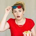 Young woman watching tv while sitting on a sofa with 3d glasses and popcorn with pleasure Royalty Free Stock Photo