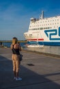 Young woman watching white ferry leaving harbor