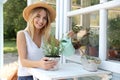 Young woman watering home plant at white wooden table