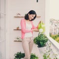 Young woman watering plant and flowers on her city balcony garden Royalty Free Stock Photo