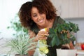 young woman watering plants at home