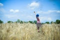 Young woman waving hand to sky on summer wheat