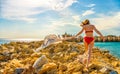 Young woman waving scarf in wind at beach. Happy woman in red bikini holding tissue and looking away at sea.