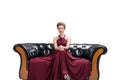 Young woman wear red dress fashion posing and sitting on black sofa looking at camera on isolated white background. Royalty Free Stock Photo