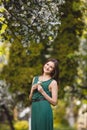 Young woman weared in long green dress in a blooming apple garden